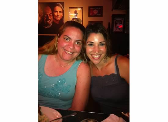 Two women friends are smiling, side by side at a restaurant